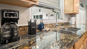 A kitchen with a coffee maker, a spice rack, and a sink. - Gem at Crystal River (Crystal River)