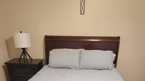 A standard hotel room with a single bed, a bedside table with a lamp, and a wall-mounted light fixture. - Gem at Crystal River (Crystal River)