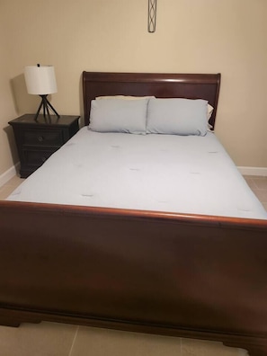A standard hotel room with a single bed, a bedside table with a lamp, and a wall-mounted light fixture. - Gem at Crystal River (Crystal River)