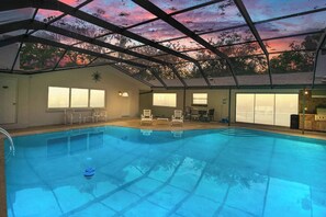 An indoor swimming pool with a glass ceiling, surrounded by lounge chairs and a barbecue area. - Gem at Crystal River (Crystal River)