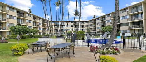 Une cour d’hôtel avec des espaces de détente en plein air, des palmiers et une piscine.