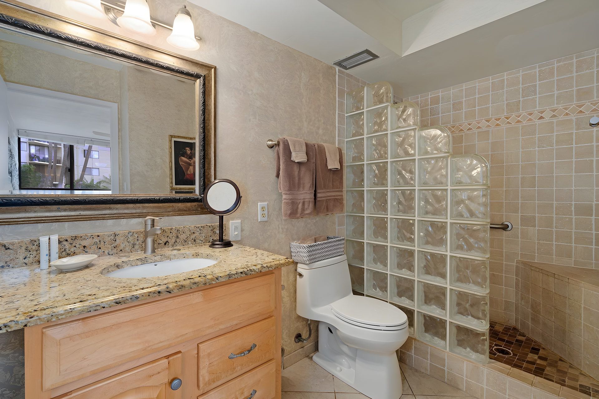 A bathroom with a double sink vanity, a toilet, a glass shower enclosure, and a large mirror.