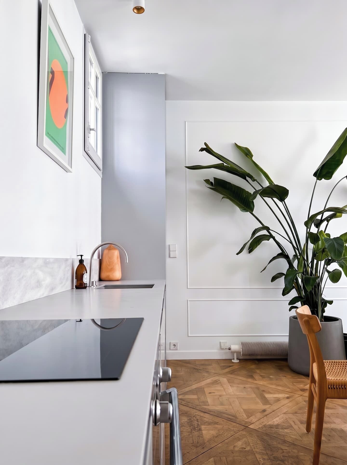 Une cuisine moderne avec un plan de travail en marbre, un évier et une plante en pot.