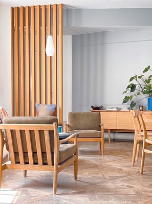 Ein modernes Wohnzimmer mit Holzmöbeln, einem Essbereich und einem großen Fenster.