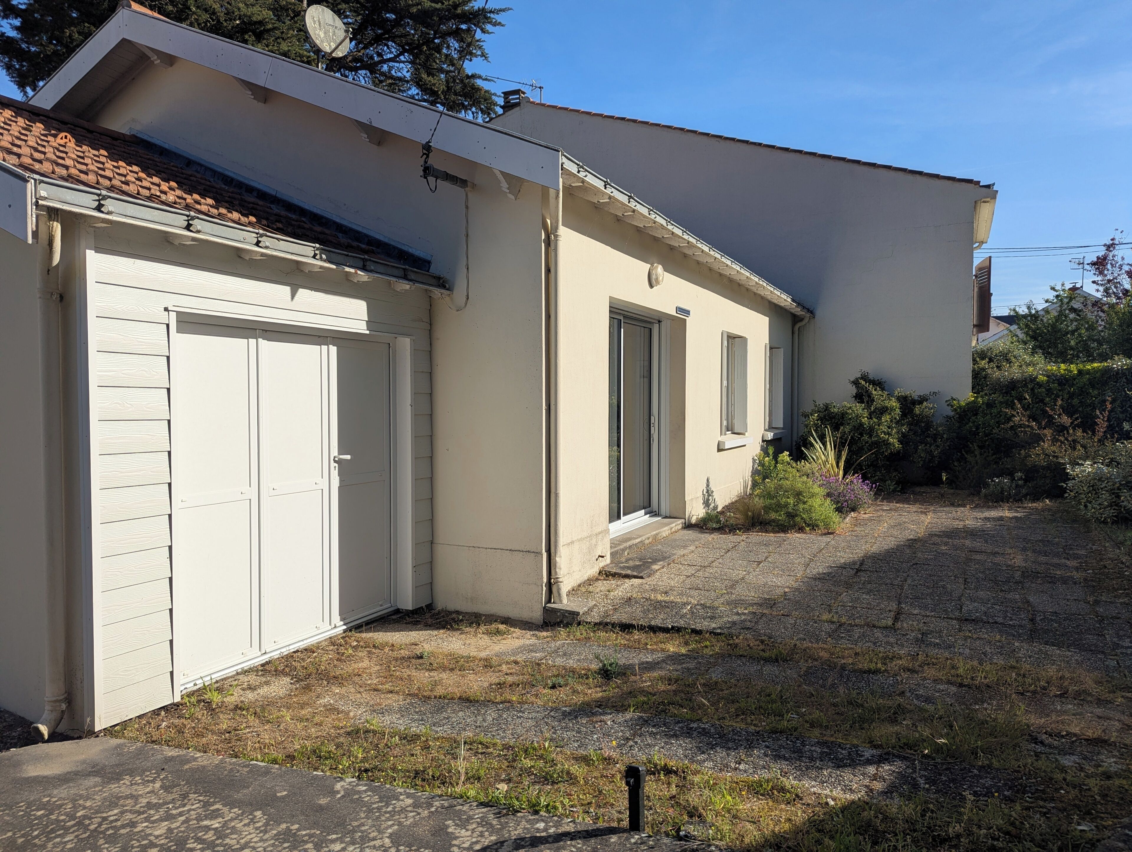 Un bâtiment à deux étages doté d’un garage, d’un porche abrité et d’un petit jardin.