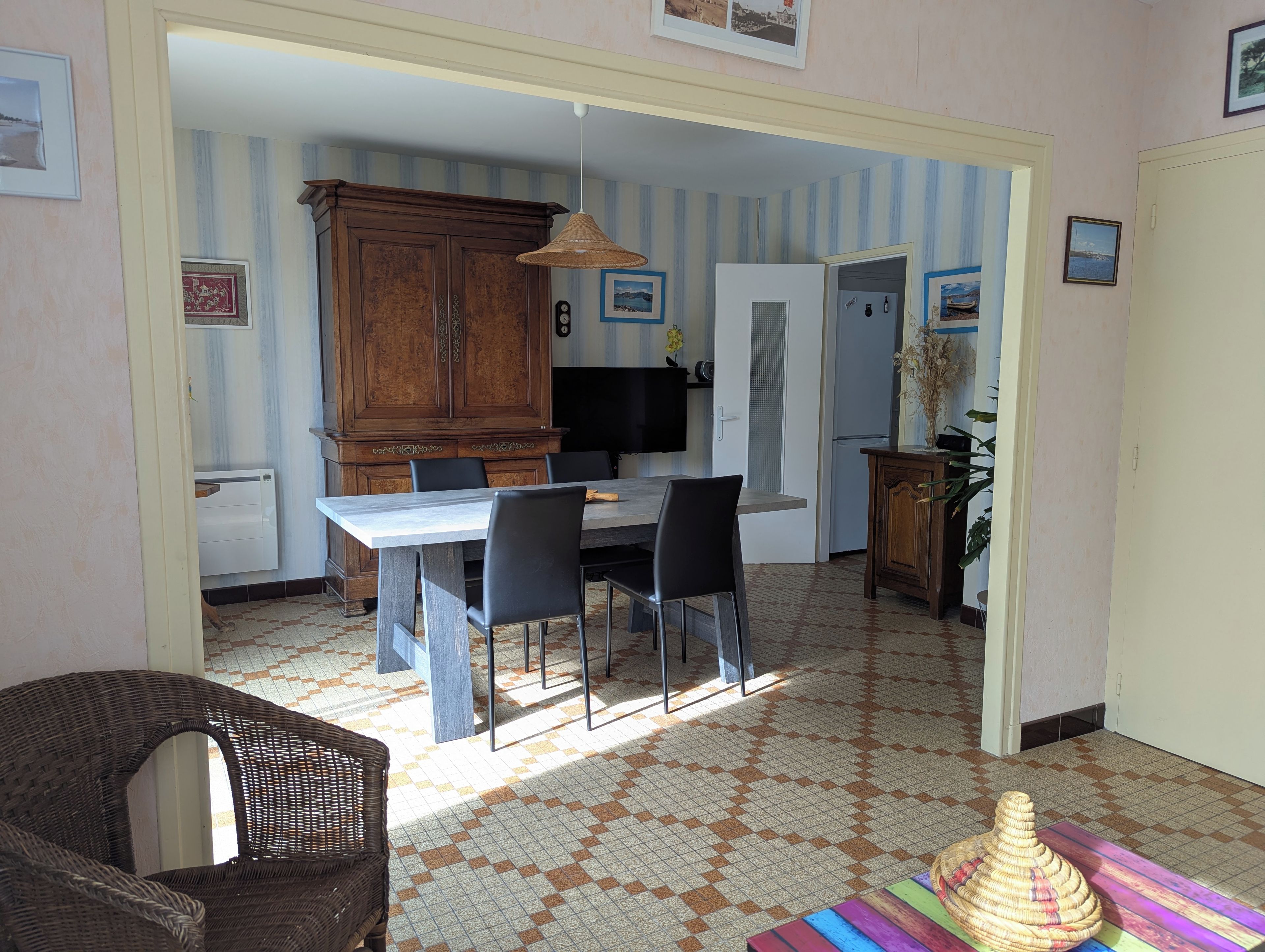 Un comedor con una mesa, sillas, un aparador de madera grande y piso estampado.