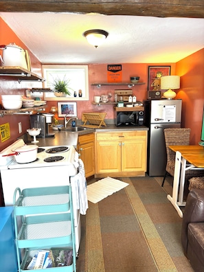 A compact kitchen with a stove, microwave, refrigerator, and wooden cabinets.