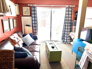 A living room with a brown leather sofa, a green coffee table, and a television on a blue cabinet.