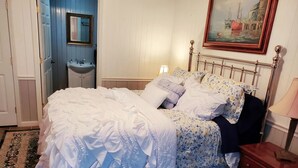 Un dormitorio con cama, mesita de noche, cómoda y un cuadro en la pared.
