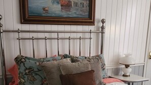 Un dormitorio con cama, un cuadro y una mesita de noche.