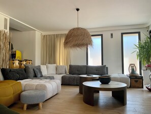 A modern living room with a sectional sofa, a round coffee table, and a hanging light fixture. - Welcome to Le Jardin des Cambrettes, a 2-hectare private estate at the gate (Lattes)