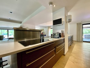A modern kitchen with a large island, built-in appliances, and a sliding glass door to the outdoors. - Welcome to Le Jardin des Cambrettes, a 2-hectare private estate at the gate (Lattes)