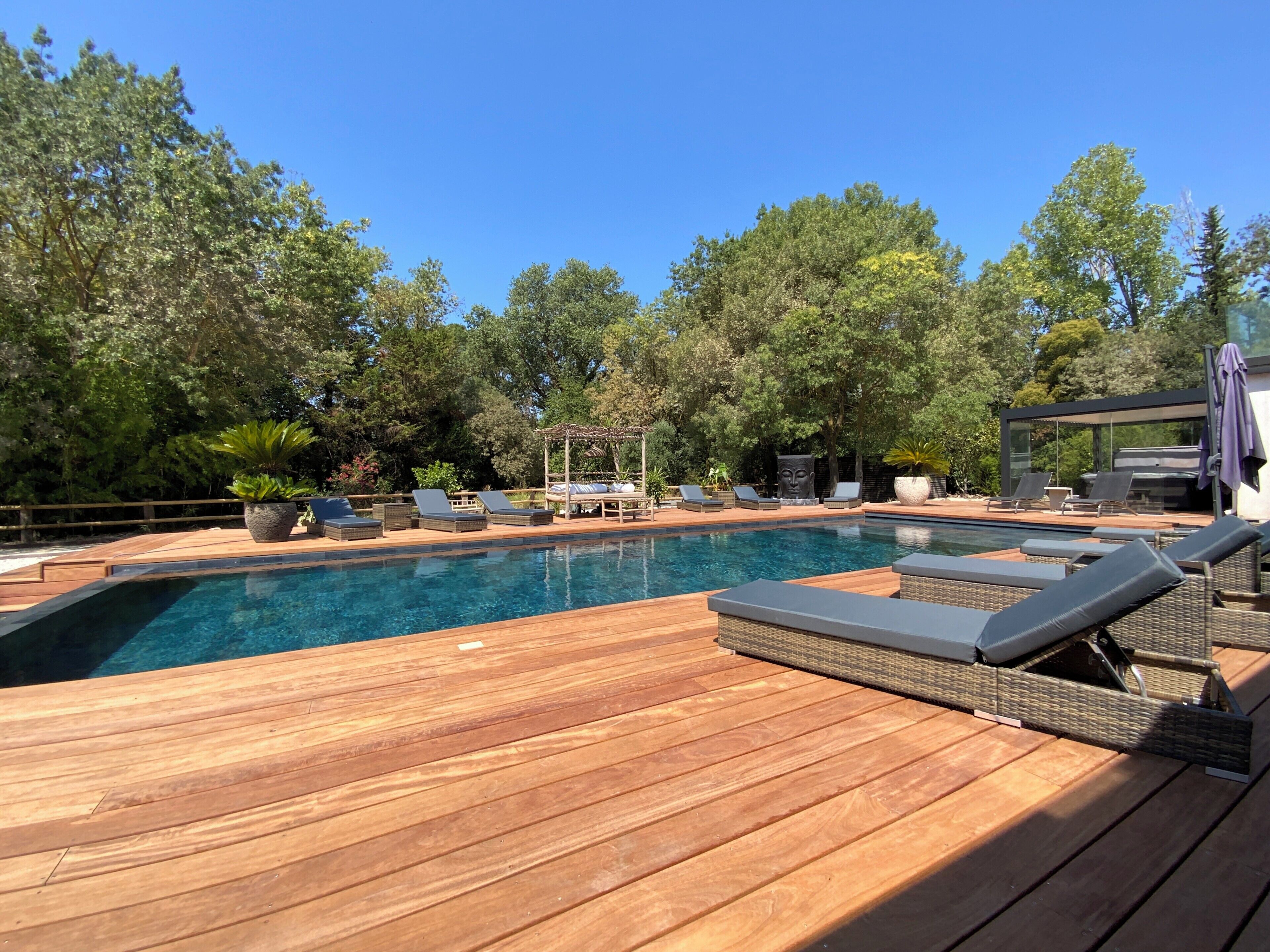 A pool area with lounge chairs and a wooden deck.