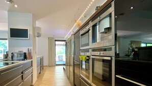 Eine moderne Küche mit Edelstahlgeräten, einem Flachbildfernseher und einer Glastür zum Balkon.
