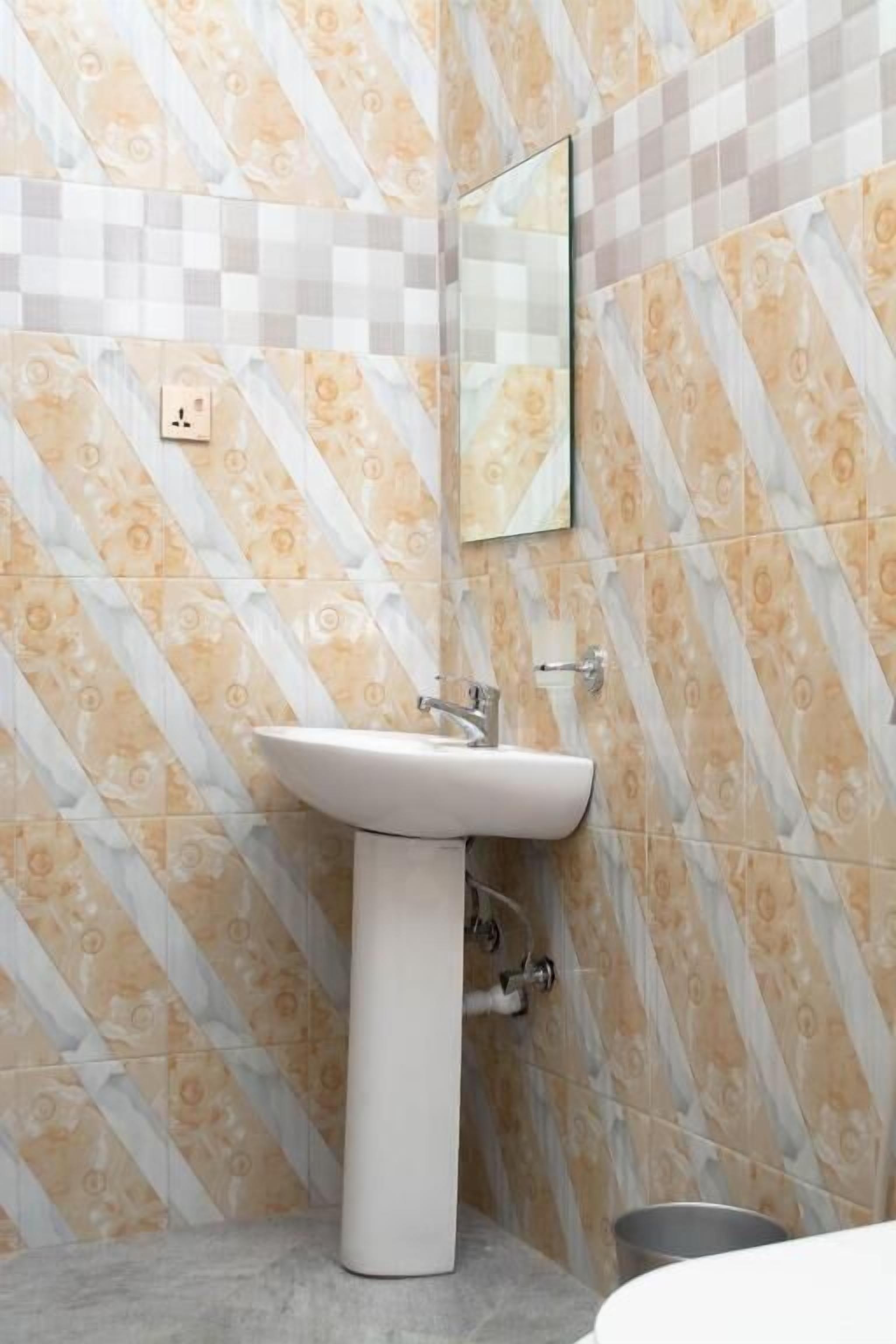 Un baño con un lavabo blanco pedestal, un espejo y azulejos estampados en las paredes.