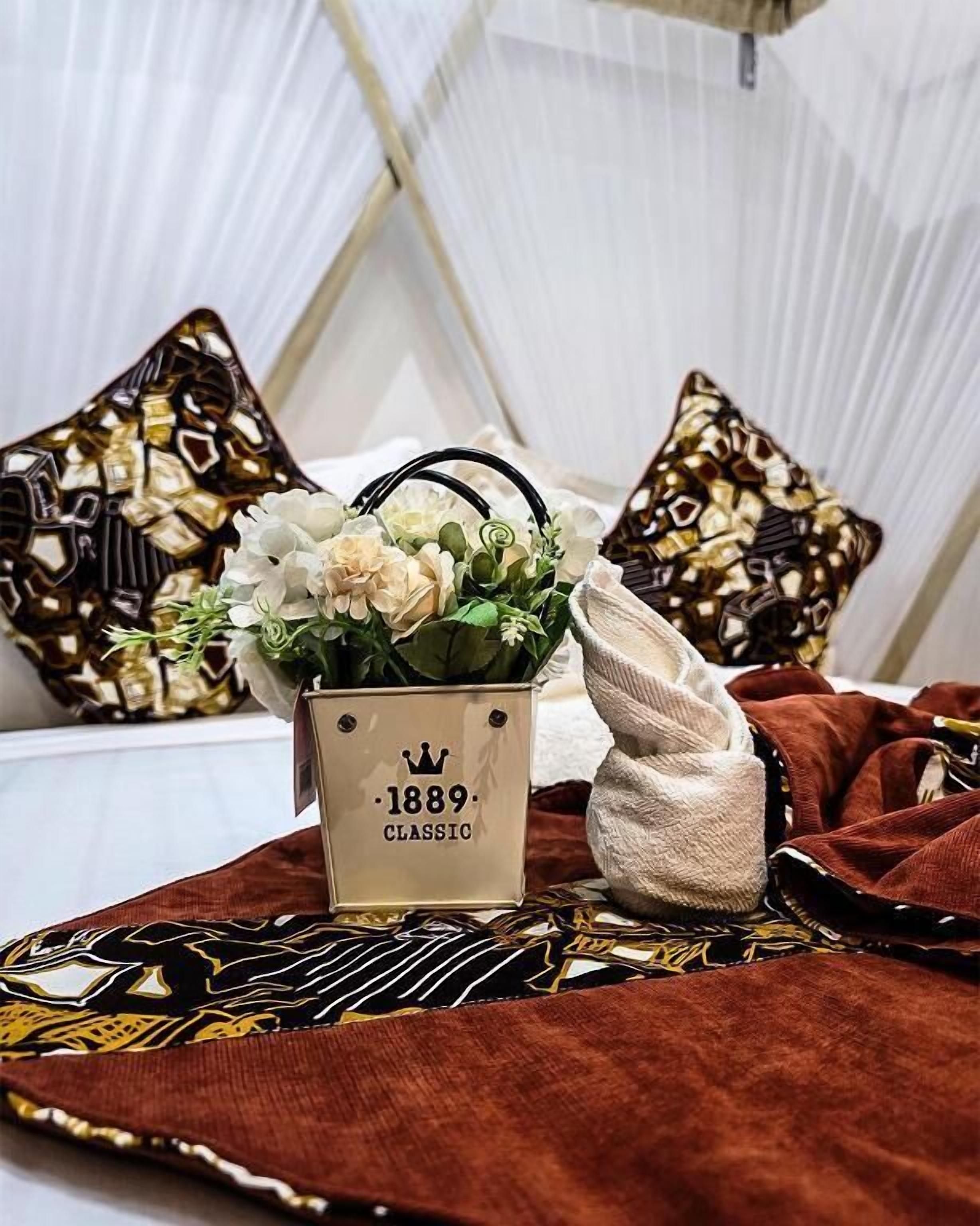 A bed with a white canopy, a decorative pillow, a small vase with flowers, and a patterned throw blanket.