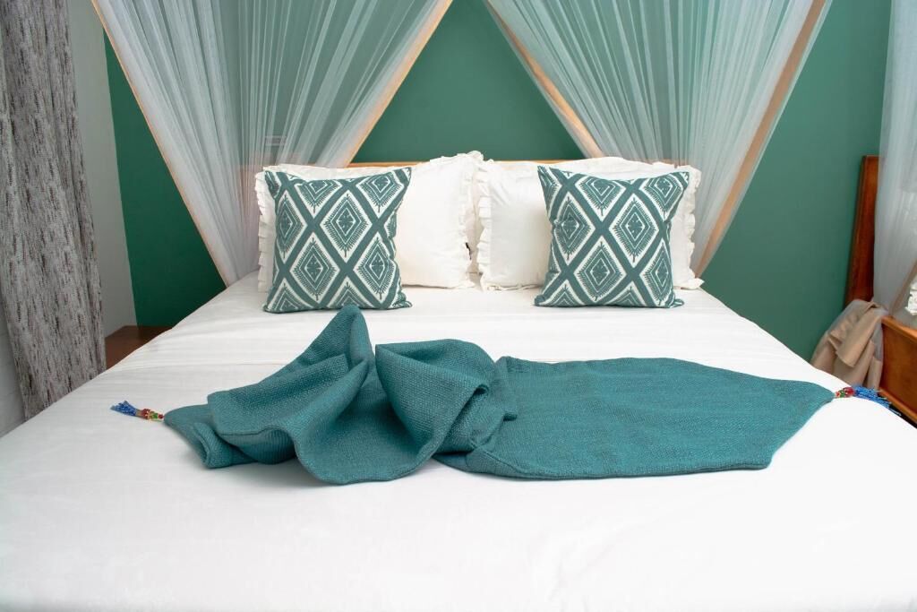 A bed with a white mattress, two patterned pillows, and a teal blanket.