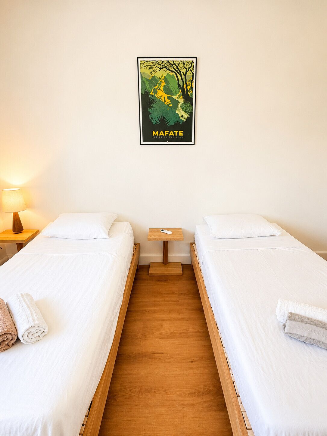Una habitación con dos camas individuales, una mesita de noche con lámpara y un cartel en la pared.