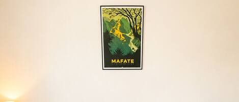 Una habitación con dos camas individuales, una mesita de noche con lámpara y un cartel en la pared.