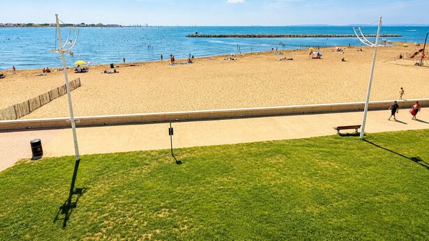 Una spiaggia con cielo sereno, spiaggia sabbiosa e area verde in primo piano.