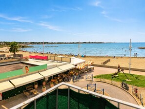 Blick auf einen Strand mit Poolbereich, Sitzgelegenheiten im Freien und Meerblick.