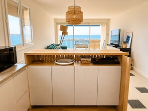 Eine Küche mit Holzarbeitsplatte, einem eingebauten Ofen und Meerblick durch ein großes Fenster.