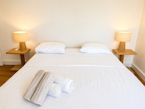 Ein Hotelzimmer mit einem großen Bett, zwei Nachttischen mit Lampen und einem zusammengerollten Handtuch auf dem Bett.