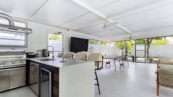 Una cocina moderna con una parrilla integrada, un fregadero y un lavavajillas. Hay una zona de comedor con una mesa y sillas.