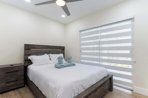 A bedroom with a bed, nightstands, a ceiling fan, and a large window with blinds. - Near Little Havana - Pool,  WFH Space (Miami)