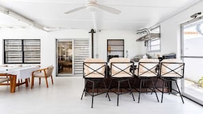A modern dining area with a white table and chairs, a ceiling fan, and a view through a glass door. - Near Little Havana - Pool,  WFH Space (Miami)