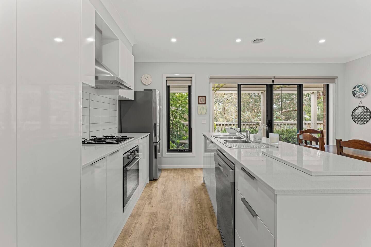 A modern kitchen with white cabinetry, a central island, and a view of greenery outside.