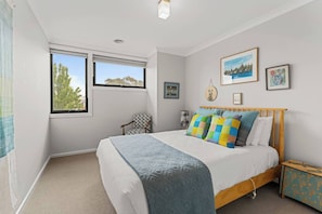 A bedroom with a bed, a chair, a bedside table, and a window. - The Pattern House Ballarat Lakeside Creative Haven (Canadian)
