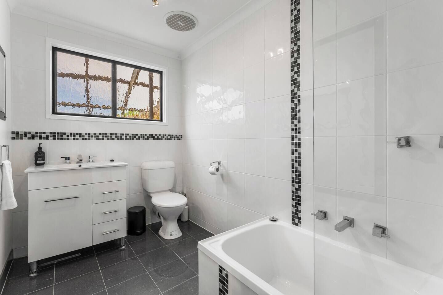 A modern bathroom with a toilet, sink, and bathtub.