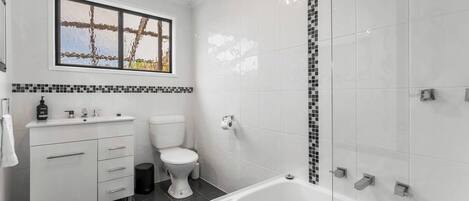 A modern bathroom with a toilet, sink, and bathtub.