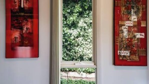 Quarto com janela, duas obras de arte nas paredes e vista para o verde lá fora.