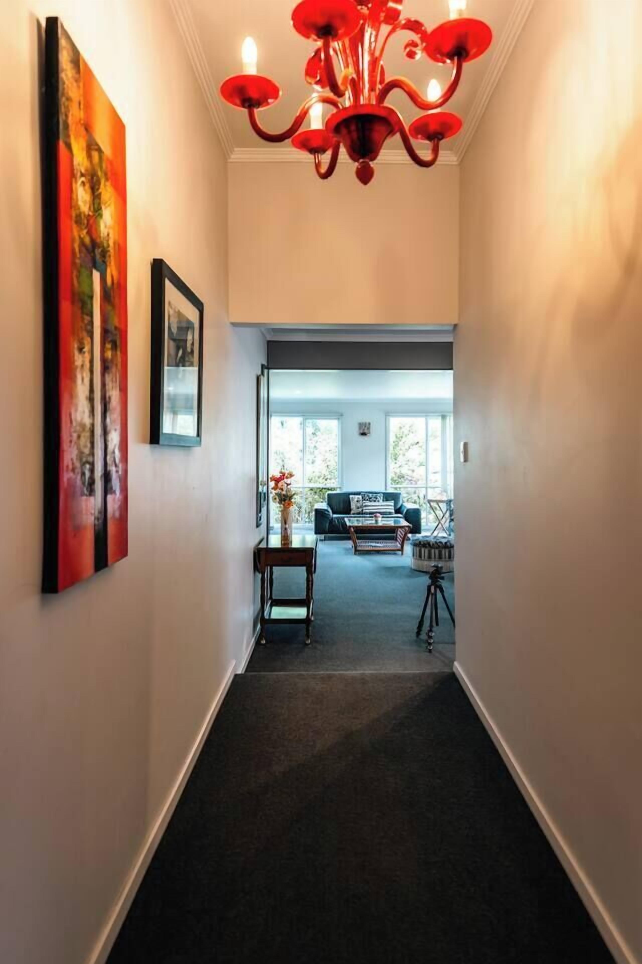 A hallway with a chandelier, artwork, and a view into a living area with furniture.