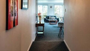 Um corredor com um candelabro, obras de arte e vista para uma sala de estar com mobiliário.