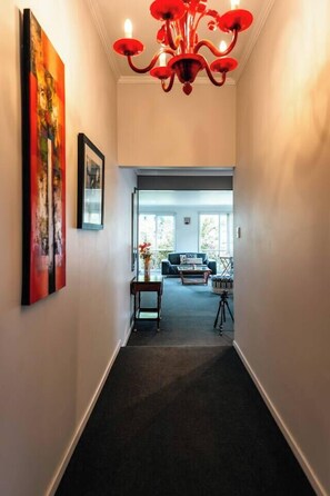 A hallway with a chandelier, artwork, and a view into a living area with furniture. - Greenview Bungalow Sunlit Stay near Sovereign Hill (Brown Hill)