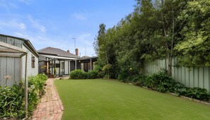 A residential backyard with a lawn, a patio area, and a wooden fence. - Greenview Bungalow Sunlit Stay near Sovereign Hill (Brown Hill)