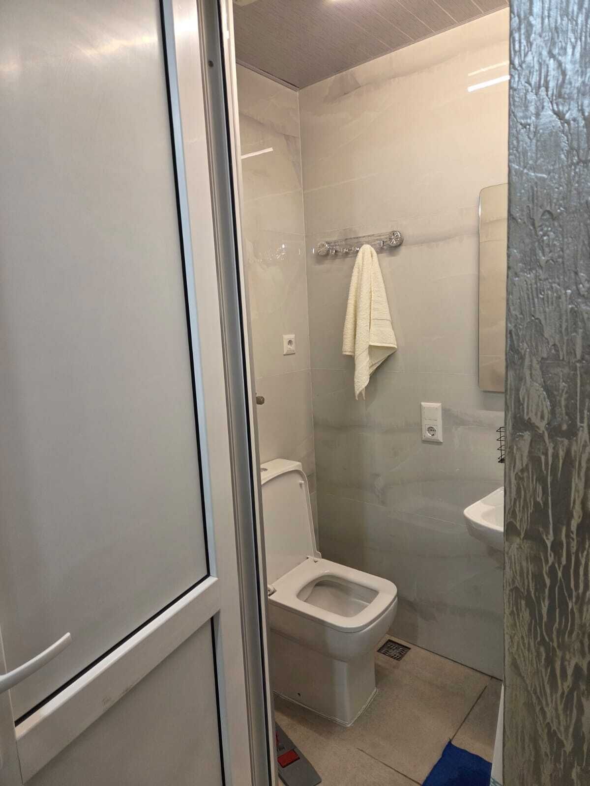 Une salle de bain comprenant des toilettes, une douche en verre et un lavabo.