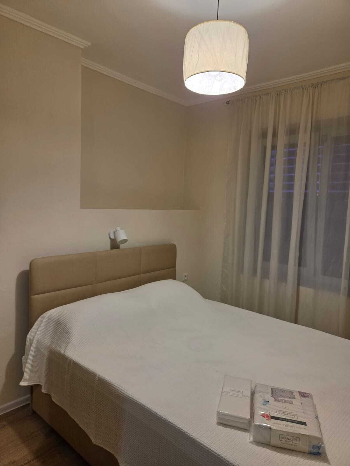 A bedroom with a bed, a bedside table, a lamp, and a window with curtains.