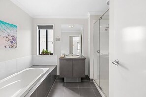 A modern bathroom with a bathtub, a sink, and a shower. - Chifley Place Modern Comfort near Delacombe Town (Delacombe)