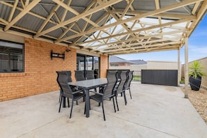 A covered patio with a table and chairs, a brick wall, and a metal roof structure. - Chifley Place Modern Comfort near Delacombe Town (Delacombe)
