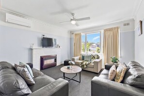 Ein Wohnzimmer mit Kamin, Ledersofas, einem Couchtisch und einem Fernseher.