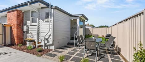 Ein Wohnhaus mit Terrasse, Sitzgelegenheit im Freien und einem Ziegelkamin.