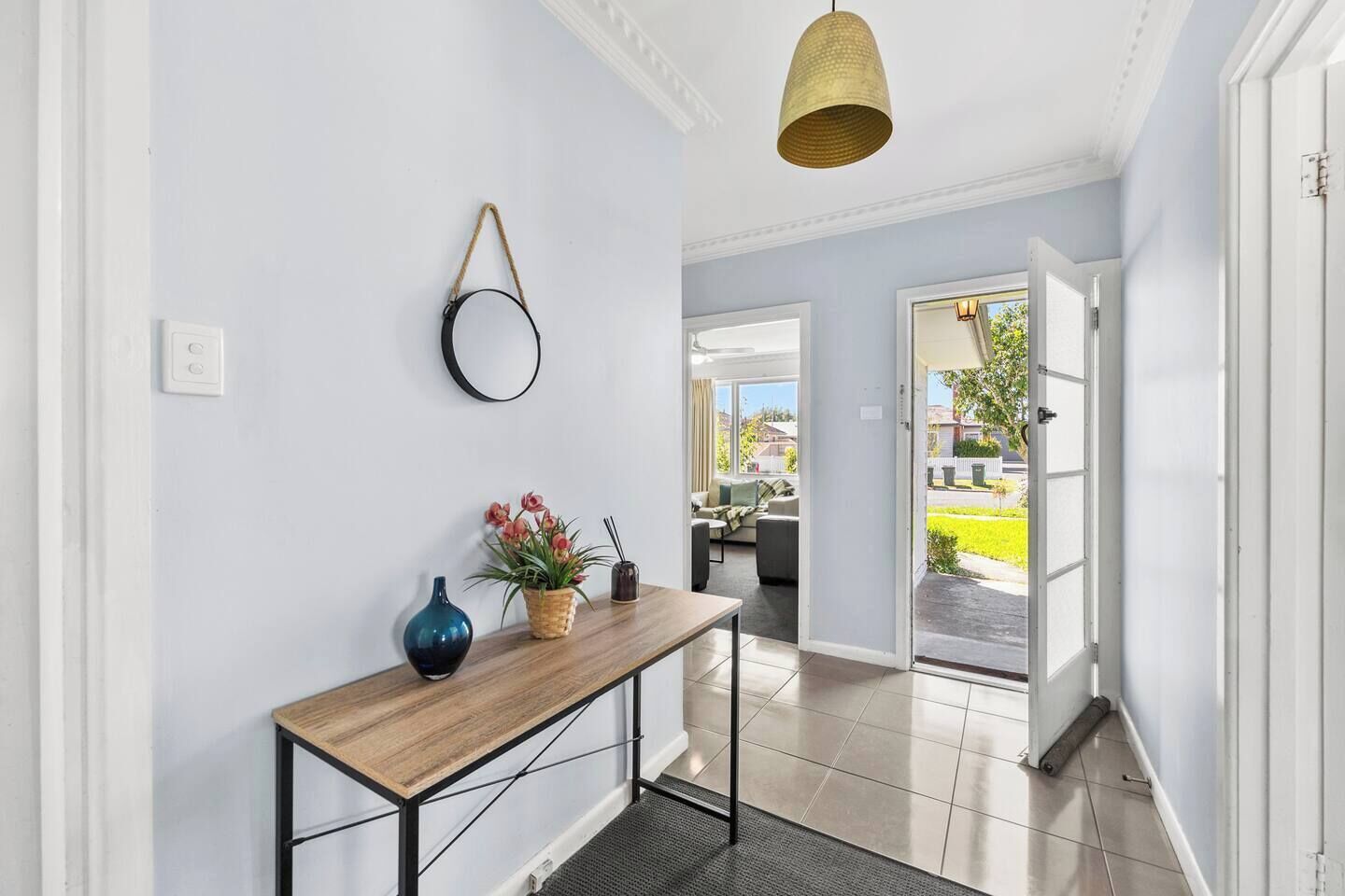 A hallway with a wooden console table, a vase, and a hanging light fixture.