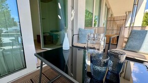 A modern room with a glass table, clear glassware, and a view of the outdoors.