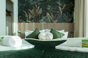 A hotel room with a bed centered between two windows, a large tropical-themed mural on the wall, and a wooden headboard. - Design Apartments Blue Ocean (Erfurt)