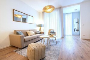 Una sala moderna con un sofá, sillones, una mesa baja y una alfombra.