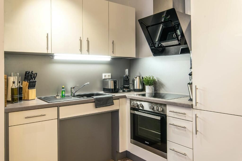 Een moderne keuken met een inbouwoven, een koffiezetapparaat en een spoelbak.